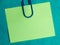 green blank note pinned to a blue notice board with a paper clip