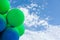 Green and blue balls balloons on cloud sky background. Vivid holiday poster with copy space. Sunny happy day concept