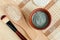 Green blue bentonite clay powder in the bowl, wooden hair brush and make-up brush. Clay texture close up.