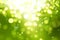 Green blurred bokeh background, white and yellow circles, glitter, nature