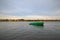 Green boat anchored in river Daugava with town Plavinas on opposite bank in autumn