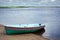 Green boat with stripes on the shore behind water