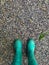 Green boots standing on a small stones floor