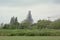 Green borders of Dender river, with tower of Saint Aldegondis church in Mespelare  under renovation