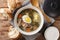 Green borsch of sorrel, vegetables, eggs with meat in a saucepan served with bread and sour cream close-up. horizontal top view