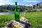 Green bottle and glass of natural Asturian cider fermented apples with view on Covadonga lake and tops of Picos de