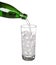 Green bottle pouring water in glass of cold mineral carbonated