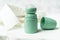 Green bottle of roll on antiperspirant deodorant lying on background of white blouse or shirt. Personal hygiene and body care