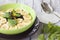 Green bowl of cereal with bananas, prunes and raisins on wood background