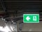 Green bright emergency fire exit with arrow show direction against metal electric wire pipe