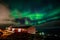 Green bright northern lights hidden by the clouds over living ho