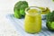 Green broccoli baby food in white bowl and jar on table. Green baby food. Child first feeding concept. Baby Natural Food