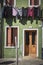 A green building with wooden doors and windows and colorful clothes hanging on the cable in Burano