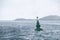 Green buoy with cone shaped topmark under snow