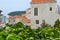 Green bushes in the foreground. Defocused ancient buildings with a red tiled roof. Old Town. Budva. Montenegro.