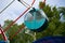 Green cabin of the round shaped Ferris wheel against the background of the blue sky.