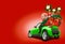 Green car on red background. Christmas tree, present boxes, balloons in form of golden stars, snow globe on roof