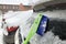 Green car snow brush cleans a layer of snow and ice on frozen car rear window.