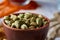 Green cardamon in ceramic bowl on white textured background close-up ,shallow depth of field.