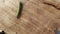 A green caterpillar walking on a wooden ground