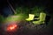 Green chairs near bonfire at night