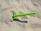 Green children`s shovel on the beach. Ready to playin the fine sands.