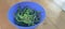 green chilies in a blue plastic bowl on a wooden table