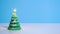 Green Christmas tree wax candle burning on blue background New Year or Christmas video banner with copy space.