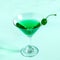 Green cocktail with maraschino cherry in martini glass