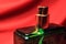 Green color perfume bottle with female accessories isolated on red background.