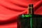 Green color perfume bottle isolated on red background. Men perfume on red silk background.