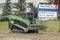 A green construction loader on a tractor flat bed