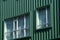 Green corrugated building facade with rectangular windows