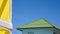 Green corrugated roof tiles of white house with part of yellow facade wall in foreground against blue sky in sunny day