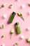 Green cosmetics packaging with ice cubes and frozen flowers on pink background. Natural beauty SPA products concept