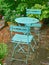 Green courtyard metal chairs and table in a serene, peaceful, lush, private backyard at home on a summers day. Patio