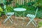 Green courtyard metal chairs and table in a serene, peaceful, lush, private backyard at home on a summers day. Patio