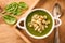 Green cream vegetable soup with croutons on wooden tray.