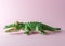 Green crocodile toy on pastel pink background. Minimal art concept