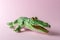 Green crocodile toy on pastel pink background. Minimal art concept