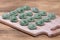 Green crude pelmeni with spirulina. Ukrainian and Russian dishes - vareniki or dumplings with beef meat or mashed potatoes or cott