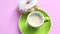 Green cup of coffee with donut on rotating pink plate