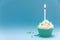 Green cupcake with candle and blue background