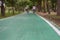 A green cycling lane in a shady park with a blurry background as people are riding a bicycle, copy space
