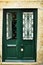 Green damaged wooden door with door knocker