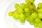 Green delicious ripe grapes on a white plate