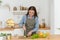 Green diet, a woman cut cucumbers. Beautiful woman preparing tasty vegetable salad in kitchen at home