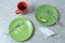 Green dirty plates and a mug with the remnants of food. On the stone kitchen countertop.