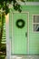 Green door and decorative wreath. Autumn welcome wreath, decorating front door home. House door with decor with leaves wreath. Aut