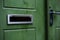 Green door with a hole for mail empty mail box